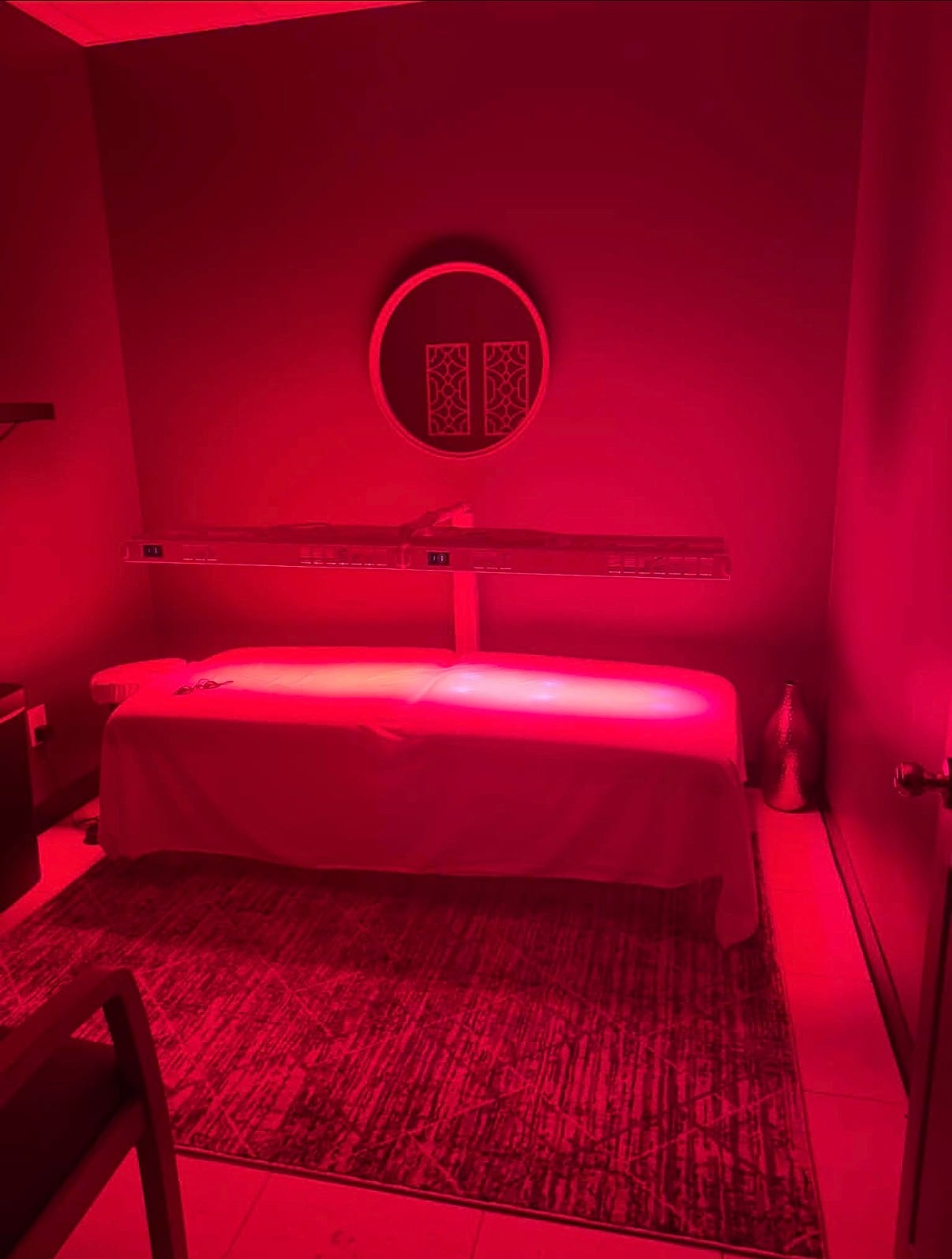 Red light therapy bed glowing inside a private treatment room